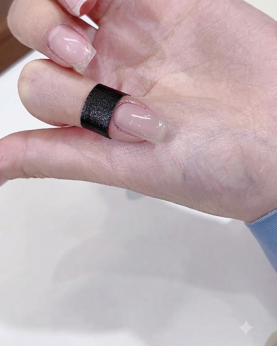Un primer plano de una uña pintada con una base de gel nude brillante.