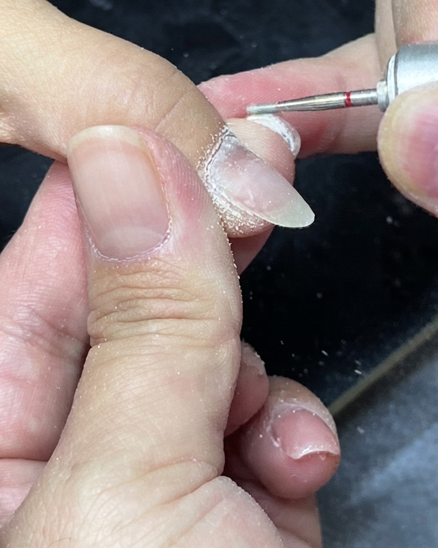 Alicates para cutículas siendo utilizados para recortar el exceso de piel muerta alrededor de los pliegues ungueales.