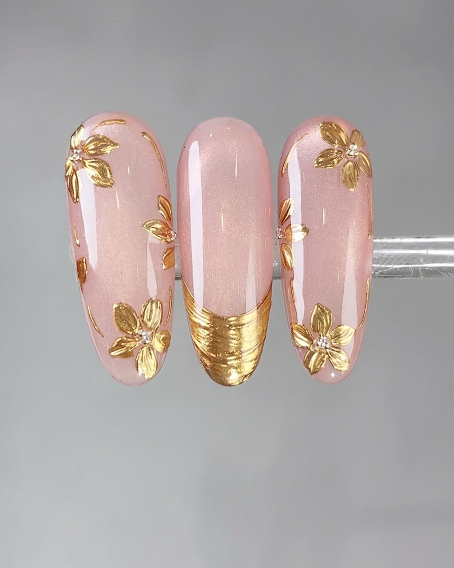 Aplicador de esponja presionando polvo efecto espejo dorado vintage sobre un diseño de uñas detallado.