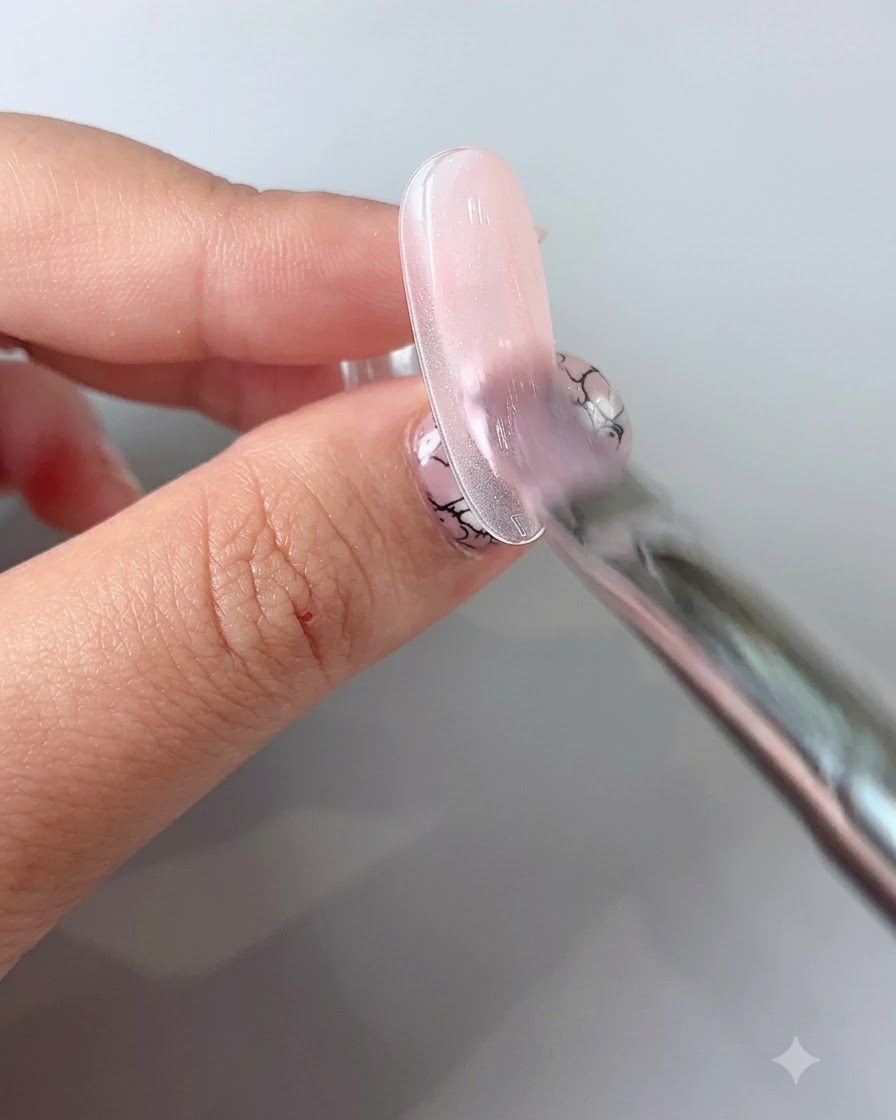 Pincel delineador fino dibujando delicadas líneas finas sobre una uña esmaltada en gel.