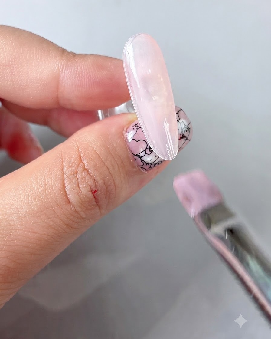 Aplicador de esponja frotando polvo dorado sobre un diseño de uñas floral curado.