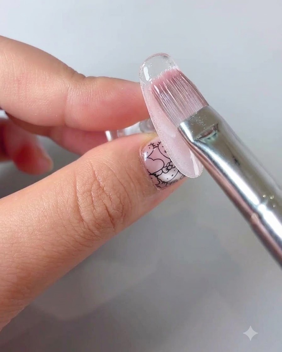 Pincel de manicura aplicando un top coat sellador transparente sobre un diseño de uñas floral.
