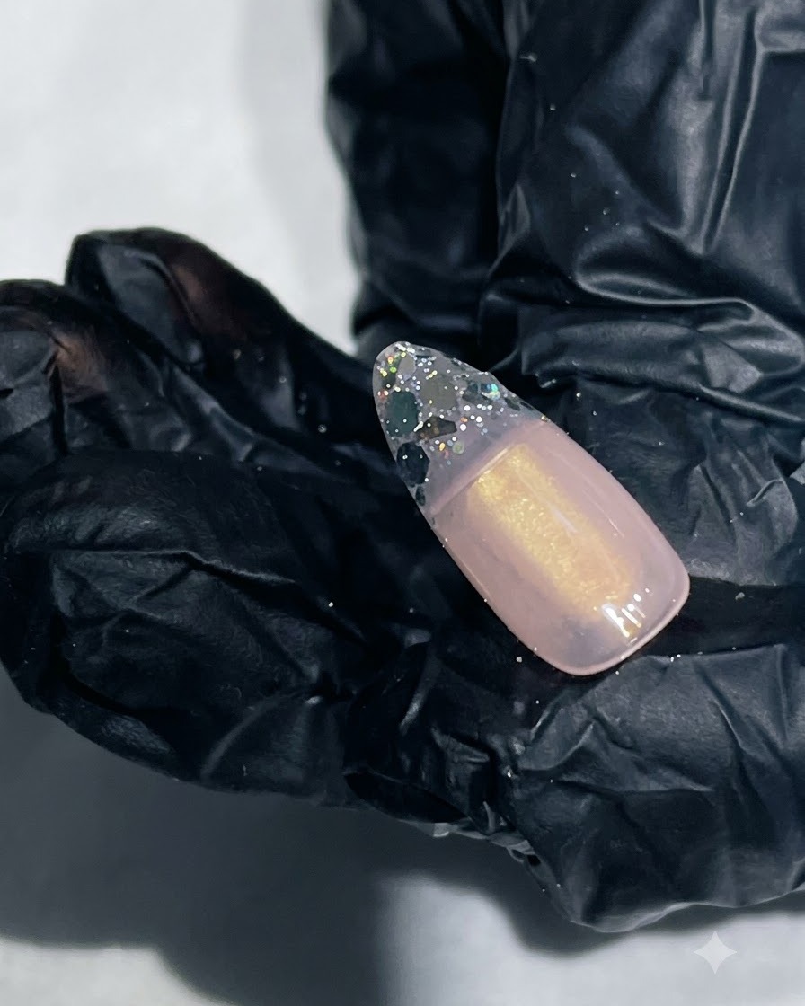 Un primer plano de una uña con gel de refuerzo liso encapsulando la punta con glitter.