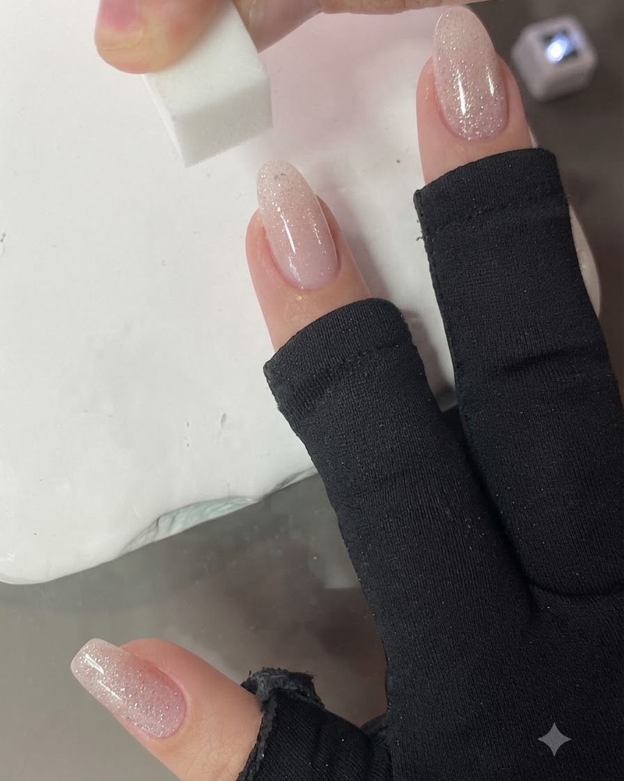 Una pequeña esponja dando golpecitos verticales sobre la uña para difuminar el degradado rosa nude.
