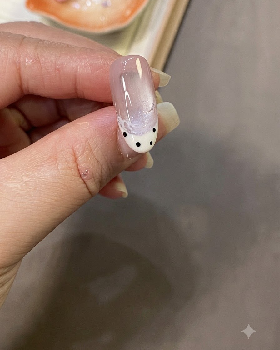 Primer plano de una mano aplicando una capa de top coat brillante sobre el diseño de uñas terminado.