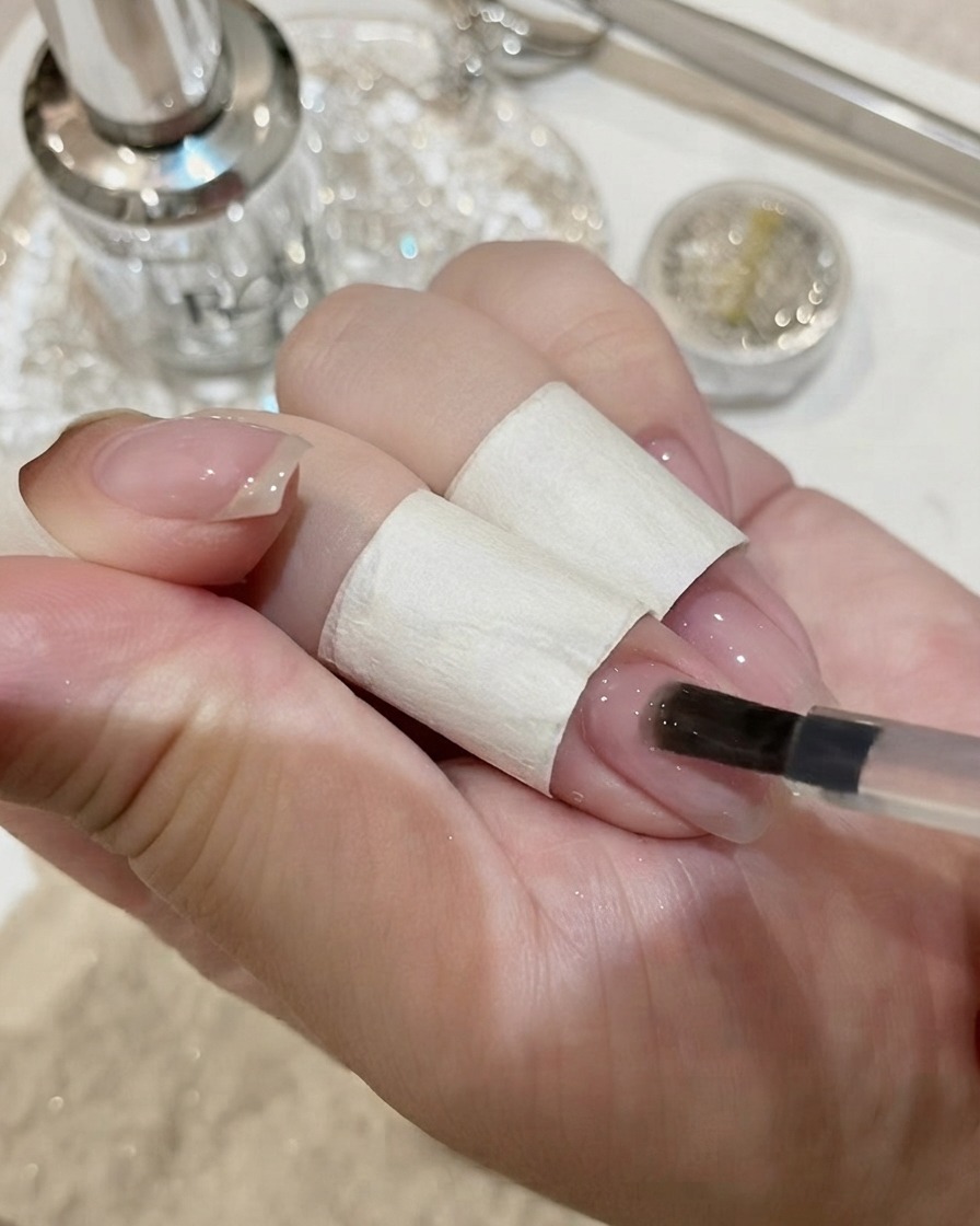 Uñas con una gran gema de cristal curándose bajo una lámpara UV.