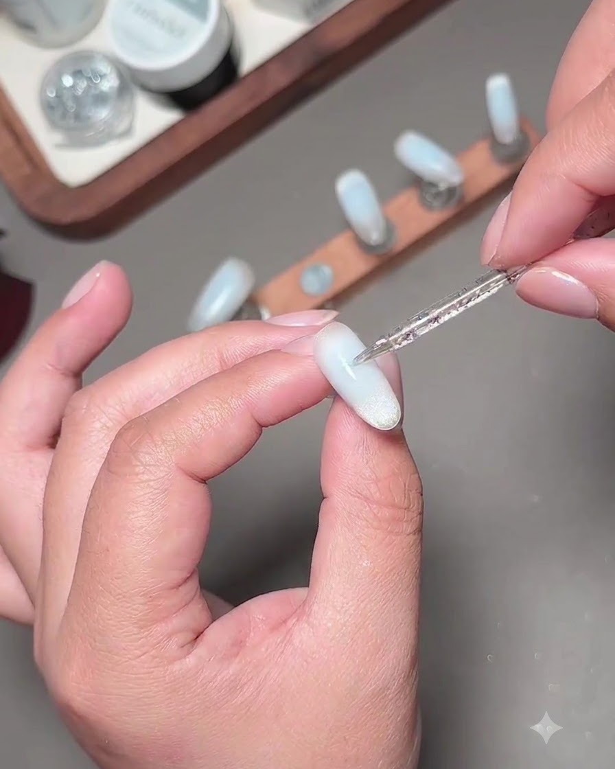 Un pincel fino de nail art aplicando una segunda capa de gel azul para oscurecer el centro de la uña.