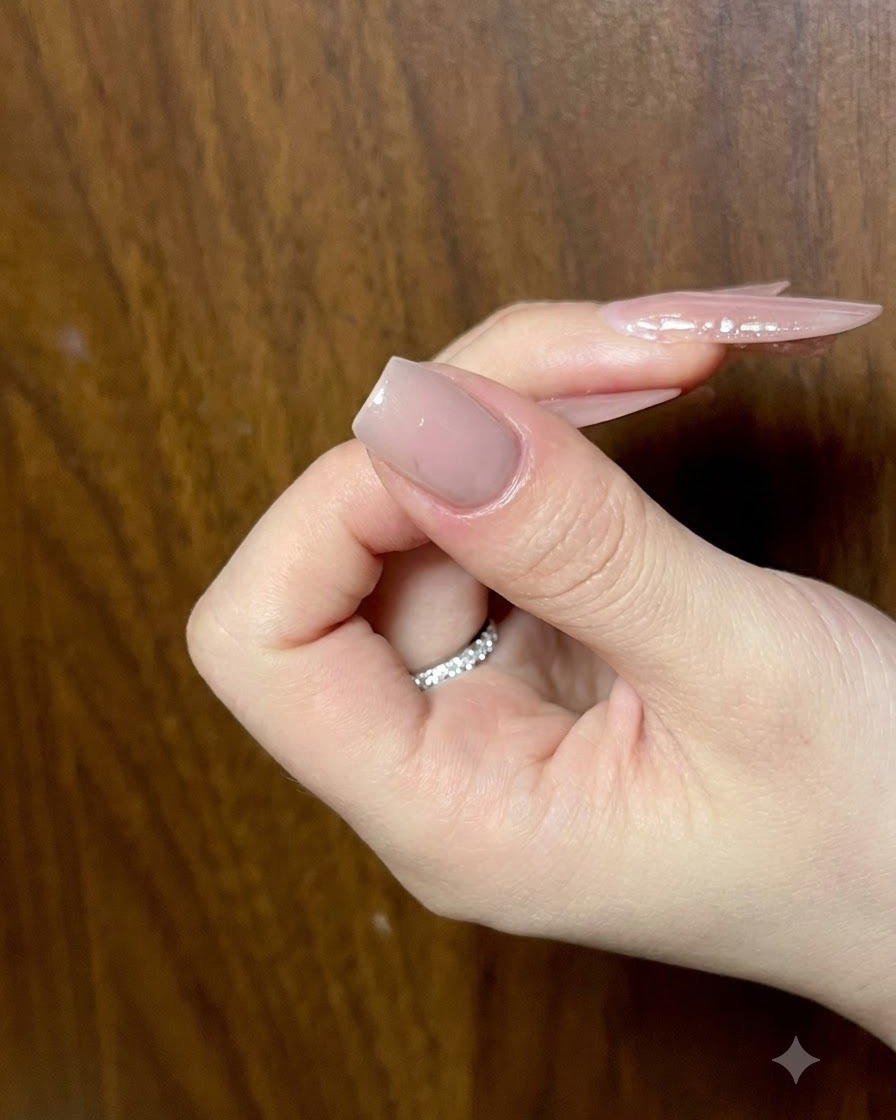 Un primer plano de una uña manicurada nude recibiendo trazos detallados de gel ojo de gato para el arte de alas de mariposa.