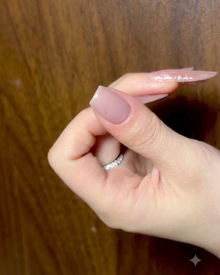 Una mano descansando con los dedos ligeramente doblados, mostrando uñas nude preparadas bajo iluminación ambiental.