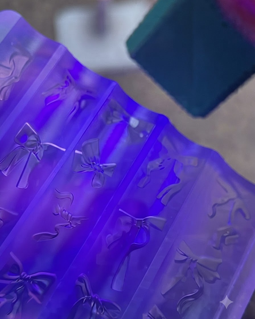 Un molde de silicona morado para uñas que contiene lazos de gel transparente colocados bajo una lámpara UV brillante.