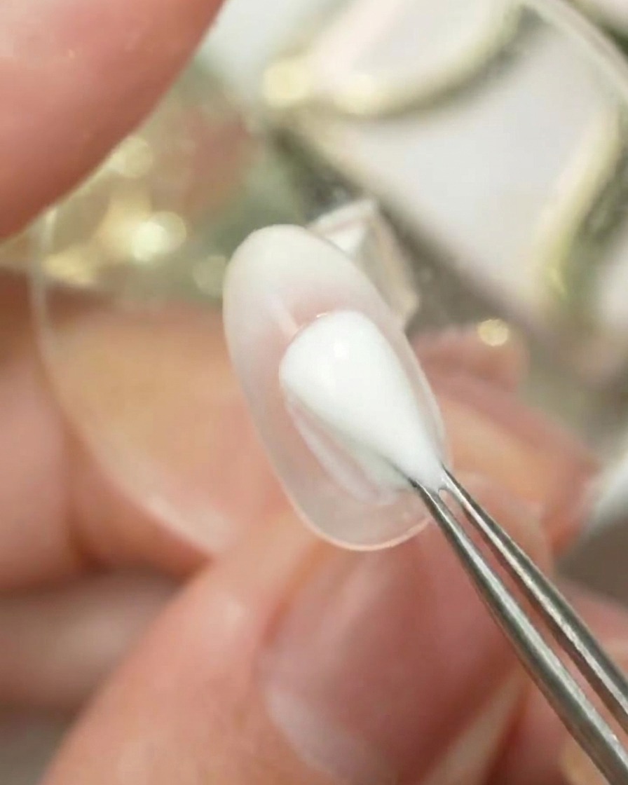 Herramienta aplicando a toques el color número 6 de la paleta Gulauri sobre la superficie de una uña transparente para crear un degradado ombré.