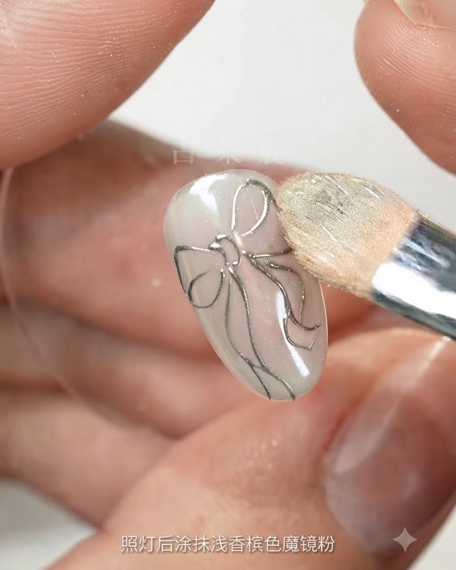 Esponja de maquillaje puliendo polvo mágico de champaña claro sobre una uña con el contorno de un lazo plateado.