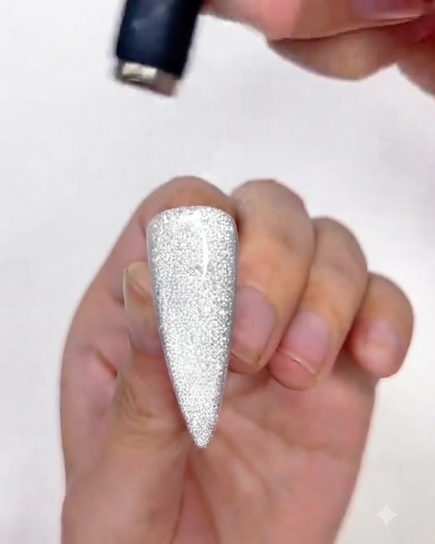 Un imán ajustando la porción superior del esmalte en gel cat-eye en la uña.