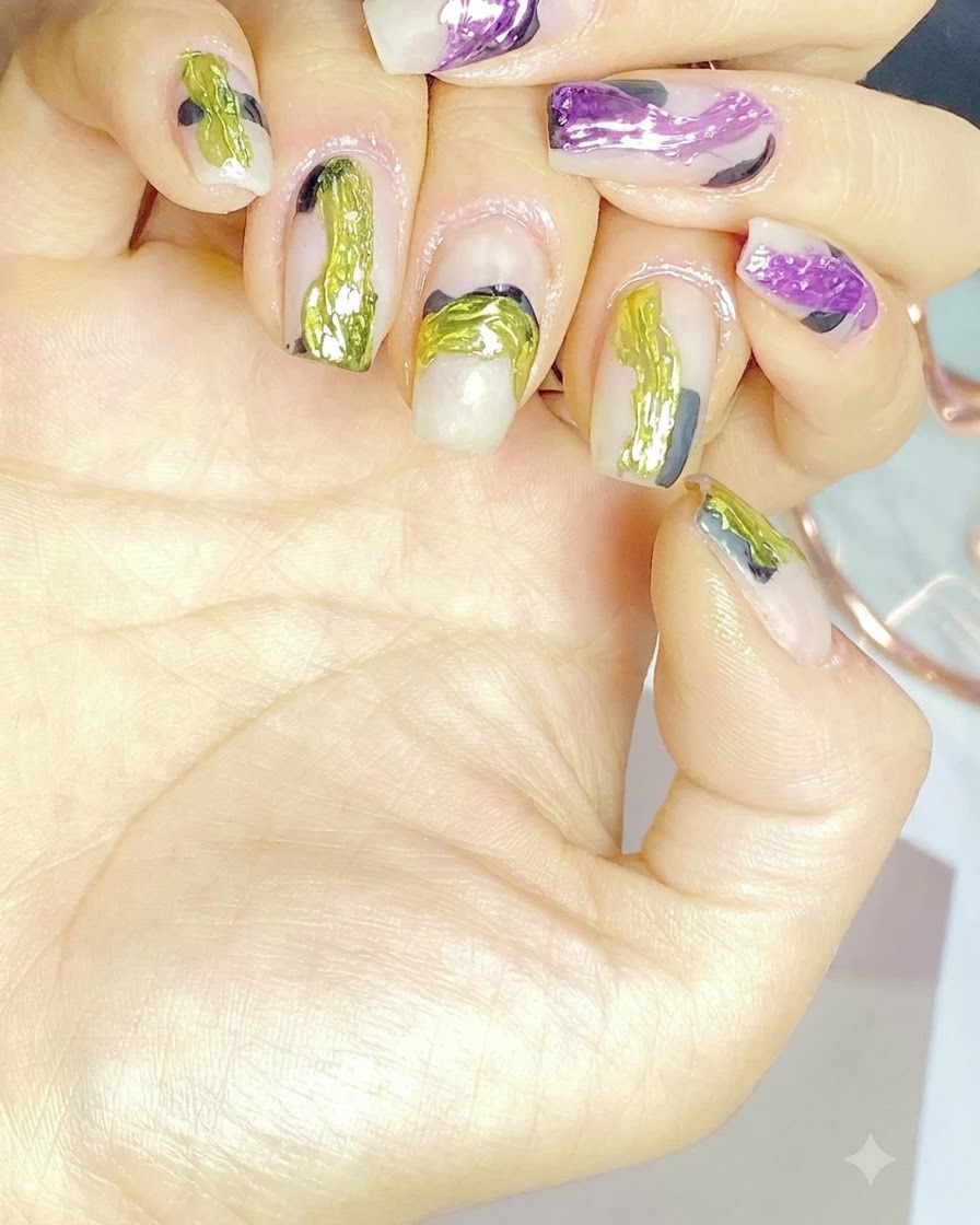 Un pincel de uñas aplicando una capa de base transparente sobre una uña natural.