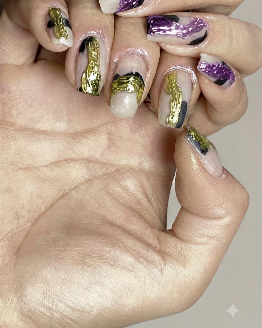 Un pincel aplicando una capa de top coat transparente y brillante sobre el nail art abstracto terminado.