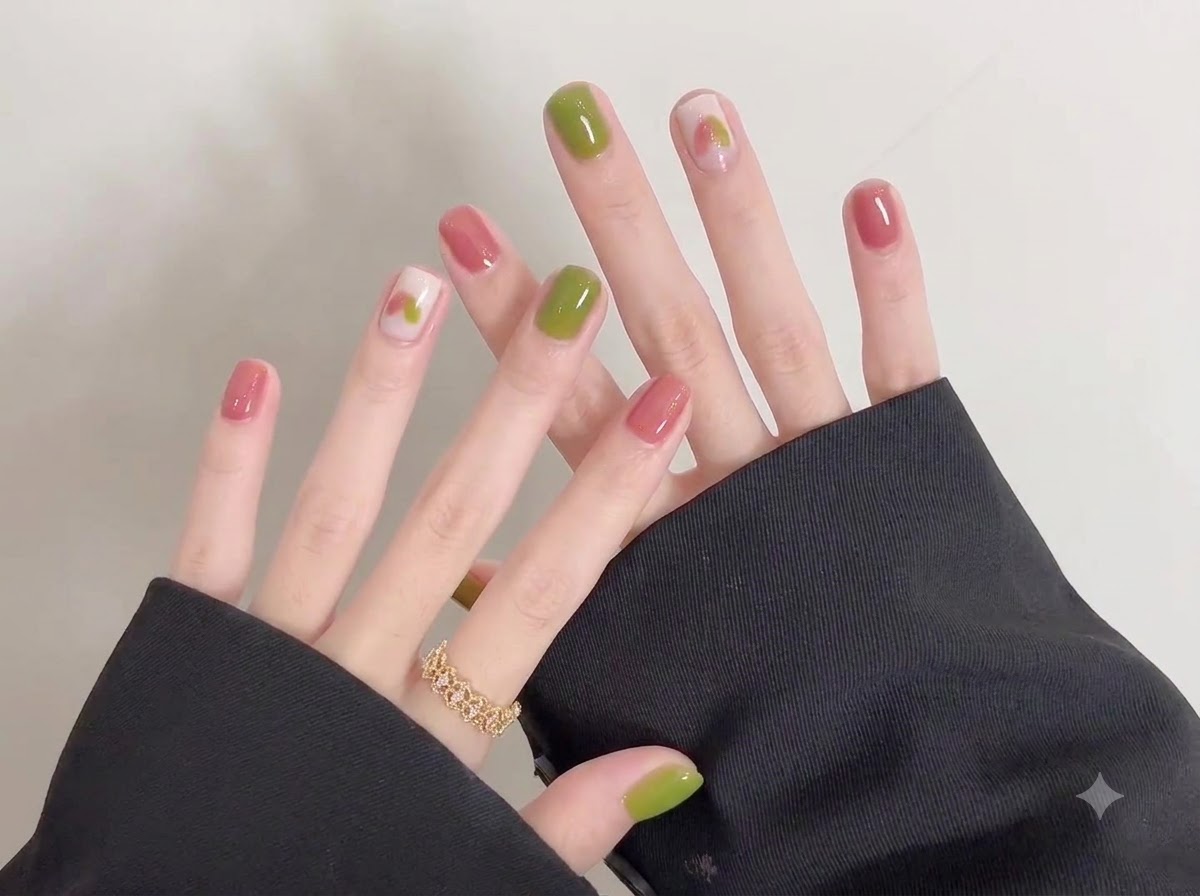 Una vista detallada de los dedos de la mano izquierda adornados con un anillo dorado junto a las uñas de gel recién esmaltadas.