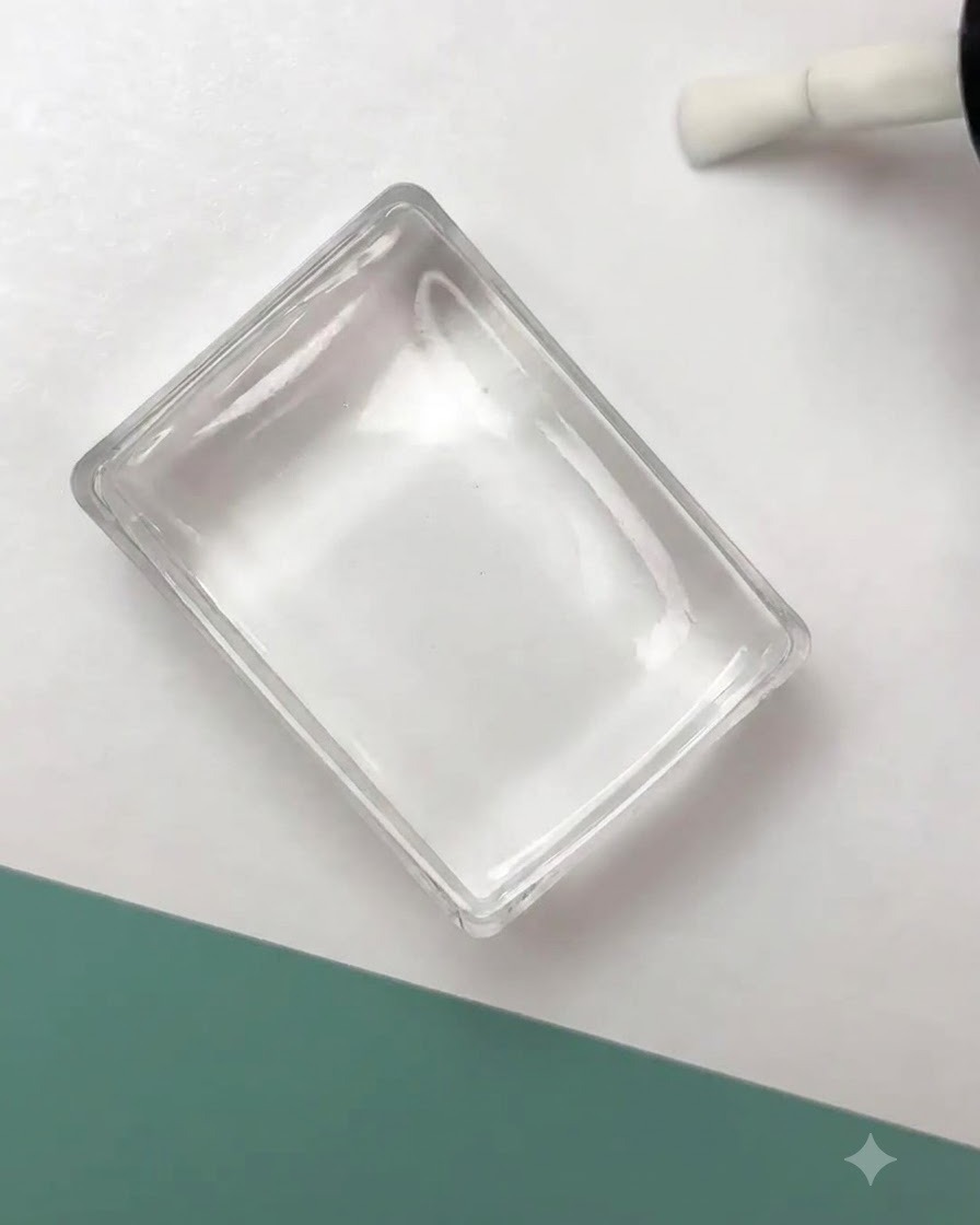 Un sello de silicona transparente presionando un diseño de contorno floral negro sobre una superficie de uña preparada.