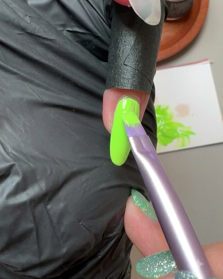Un pincel aplicando gel sólido verde fluorescente en la uña del dedo meñique.