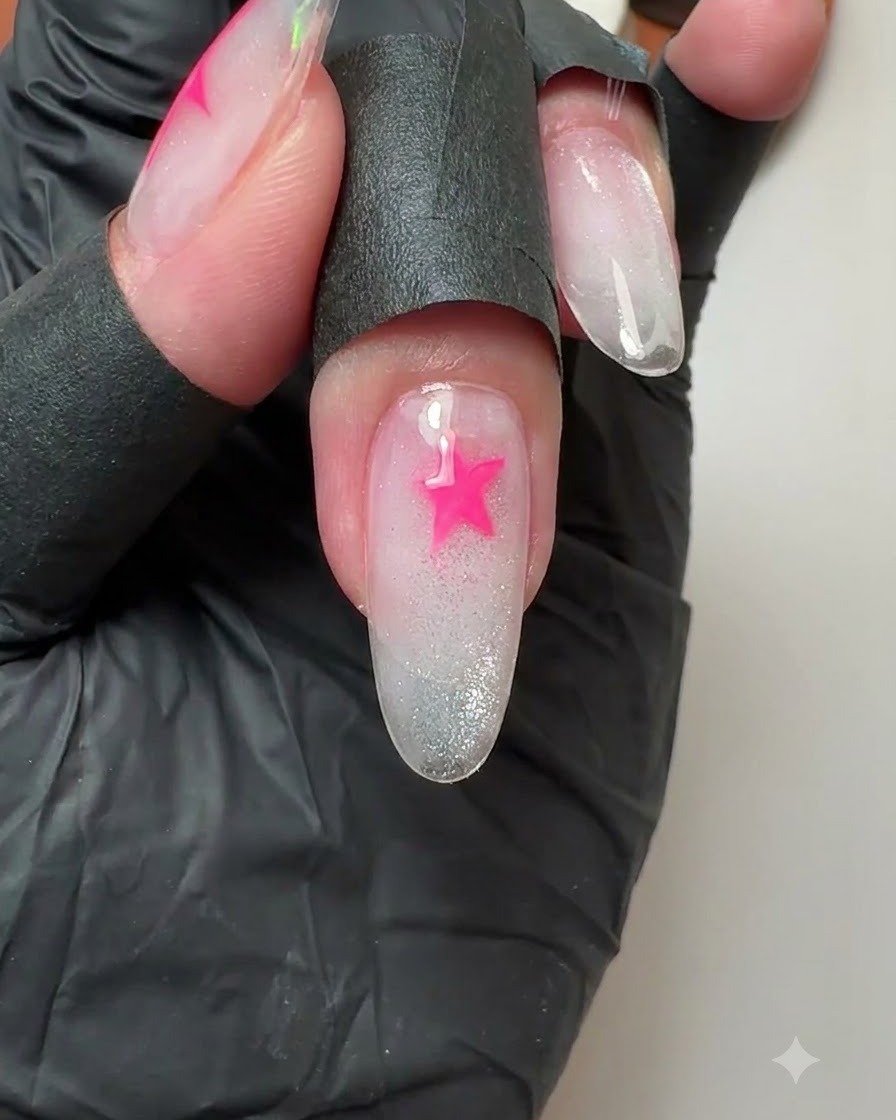 Un primer plano de una uña del dedo medio que muestra una estrella rosa vibrante recién pintada.