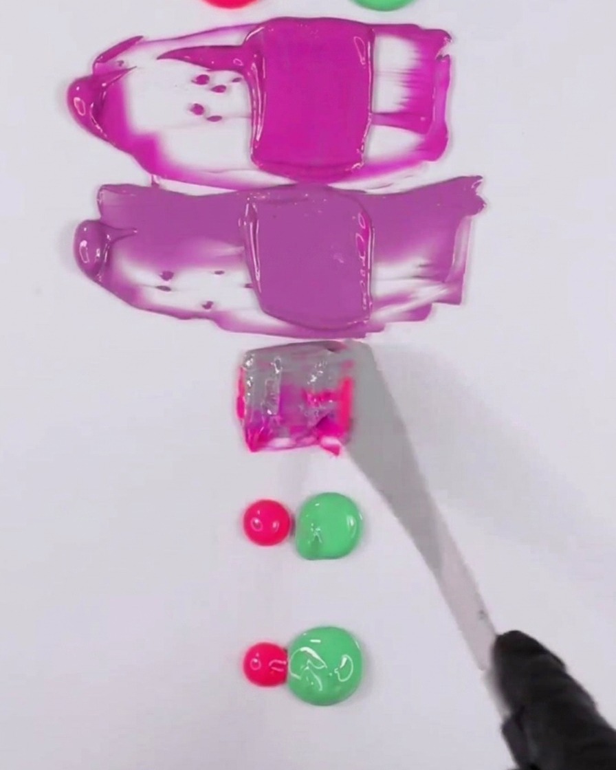 Una espátula metálica mezclando una combinación de esmalte en gel rosa y verde para crear un tono morado apagado.