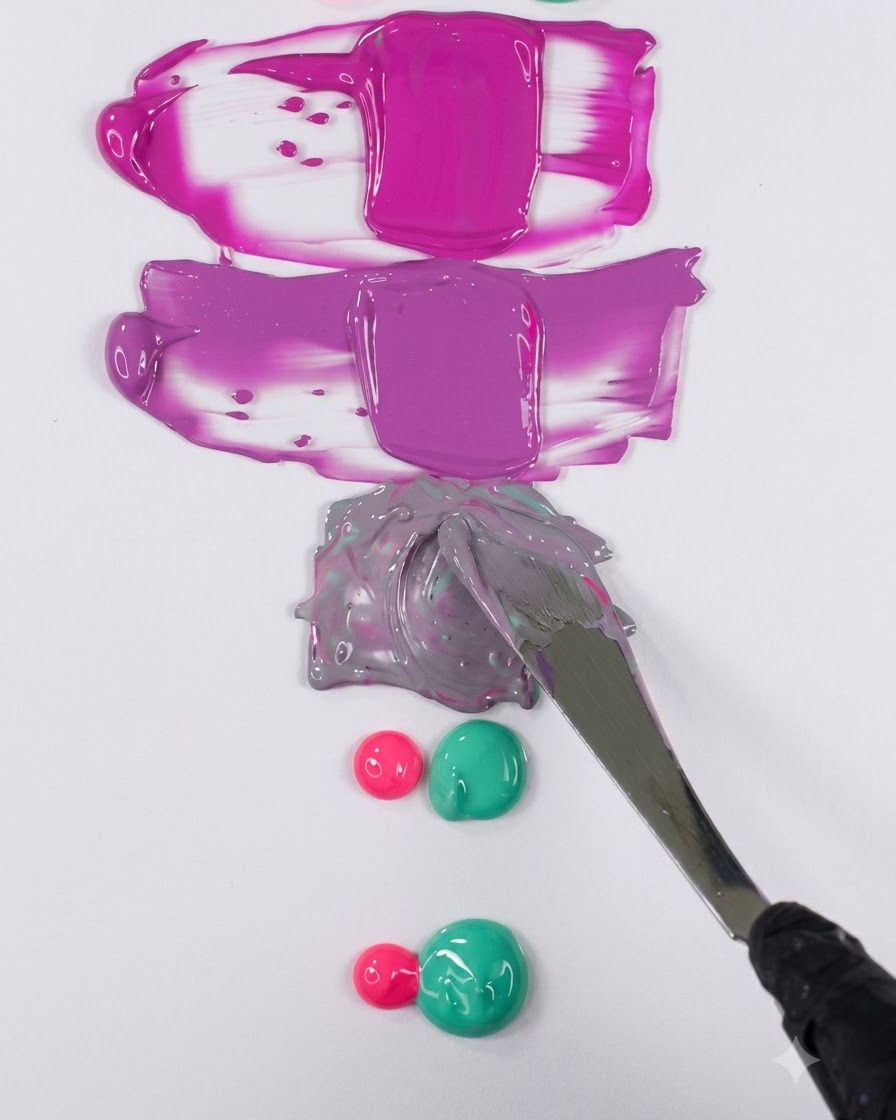 Una espátula metálica alisando una mezcla de gel morado apagado en una muestra horizontal limpia sobre una superficie blanca.