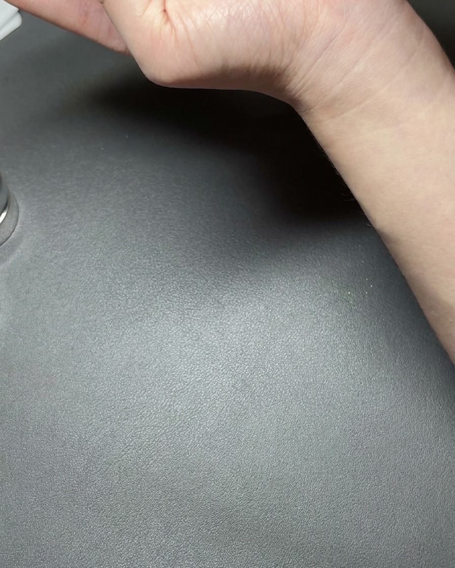 Una mano sosteniendo un pequeño imán de neodimio cerca de una uña recubierta con gel verde metálico de ojo de gato, creando una línea reflectante brillante.