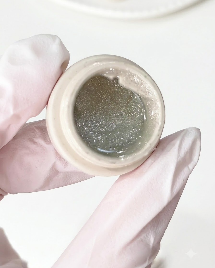 Un pincel aplicando gel de diamante triturado sobre una base de uña preparada.