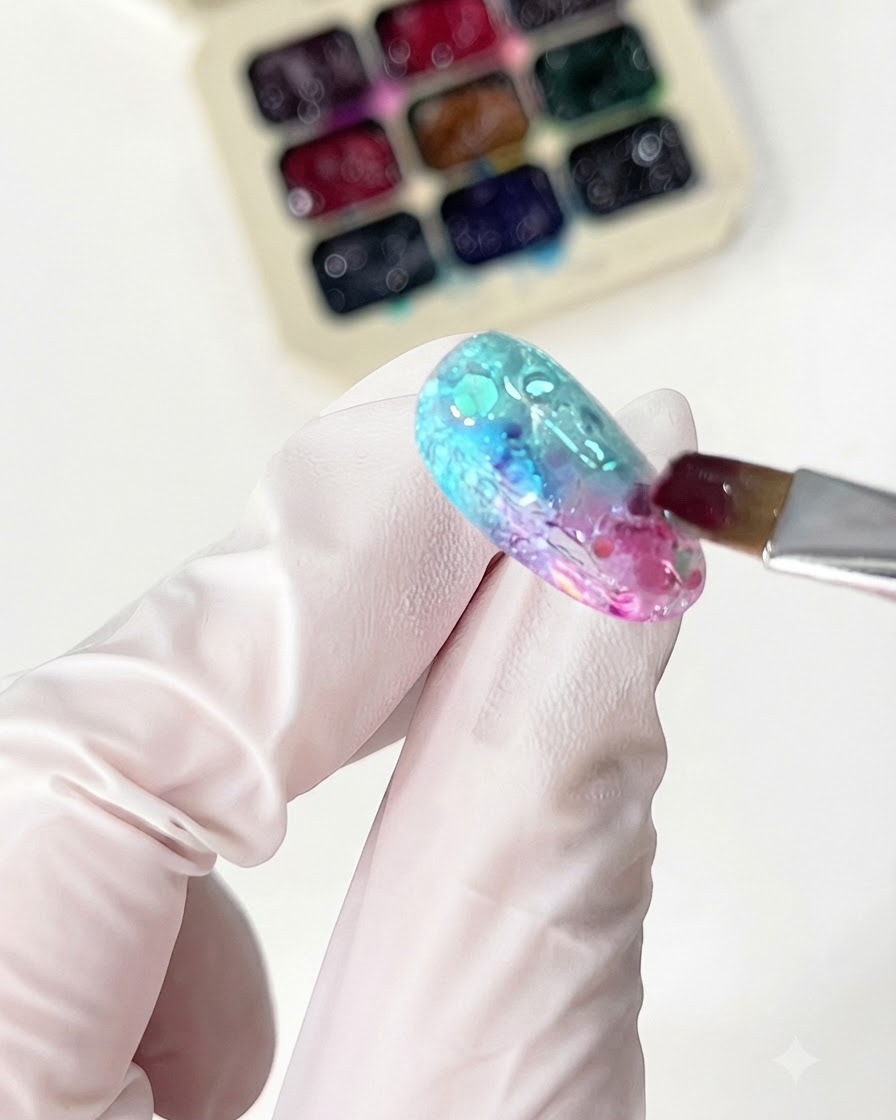 Un pincel fino aplicando gel de vidrio naranja para completar el diseño de degradado.