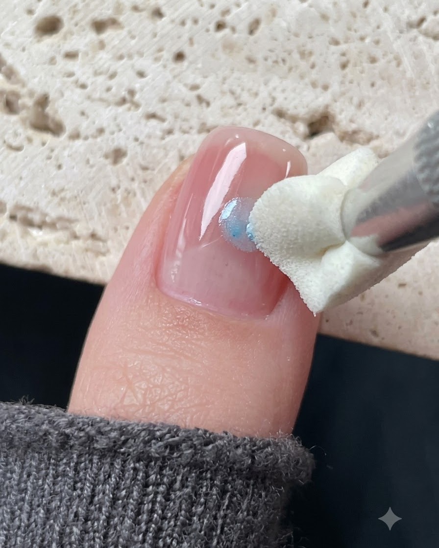 Una herramienta de estampado de silicona aplicando gel de vidrio azul alrededor de una calcomanía de estrella en una uña.