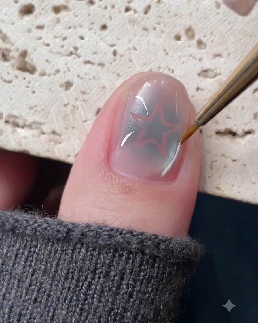 Un pincel delineador fino dibujando delicadas líneas blancas y plateadas alrededor de un diseño de uña de estrella hueca.
