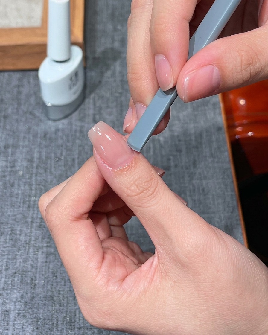 Un dedo colocado bajo una mini lámpara UV/LED para el curado.