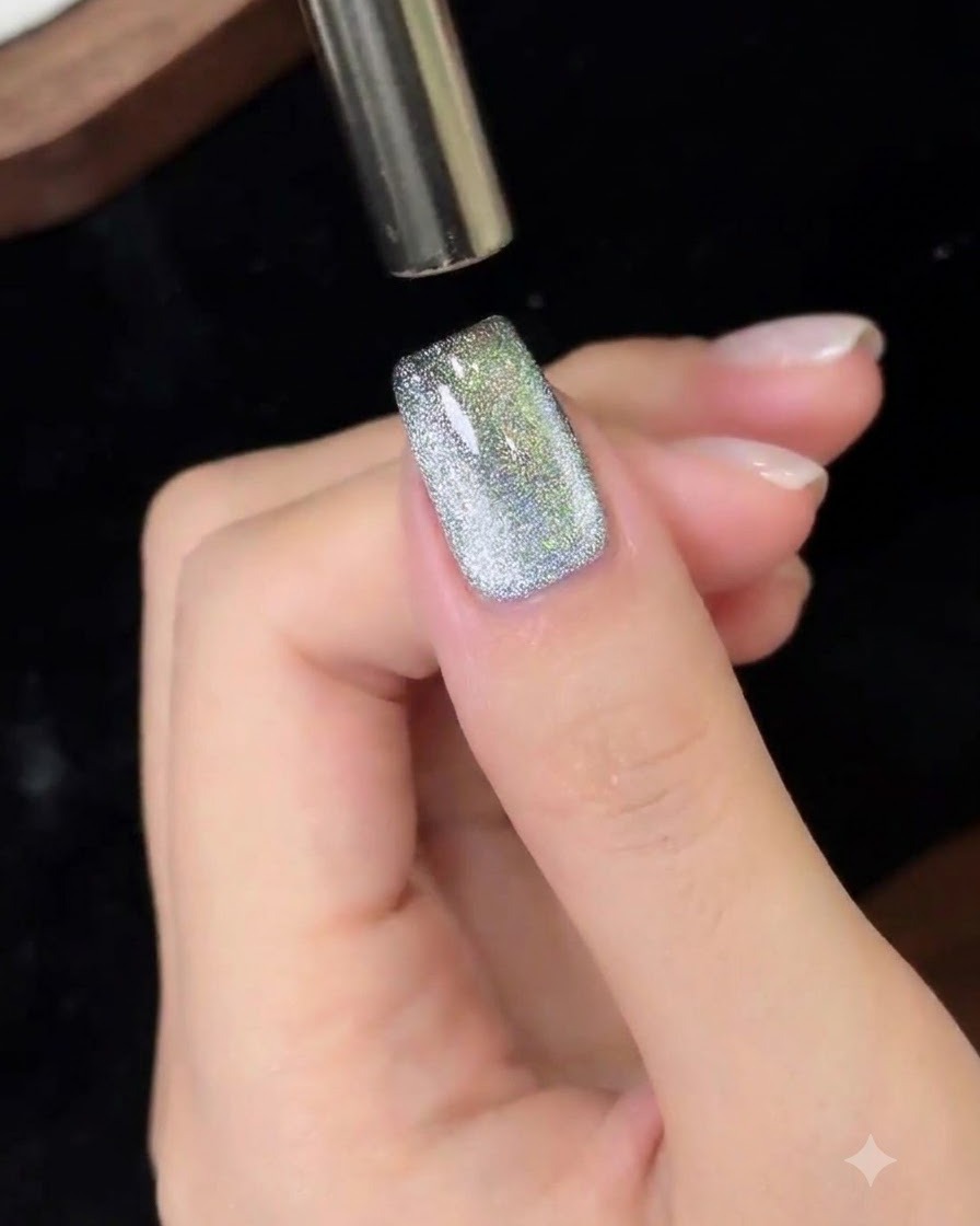 Una herramienta magnética moviéndose de arriba a abajo sobre una uña con gel cat eye.