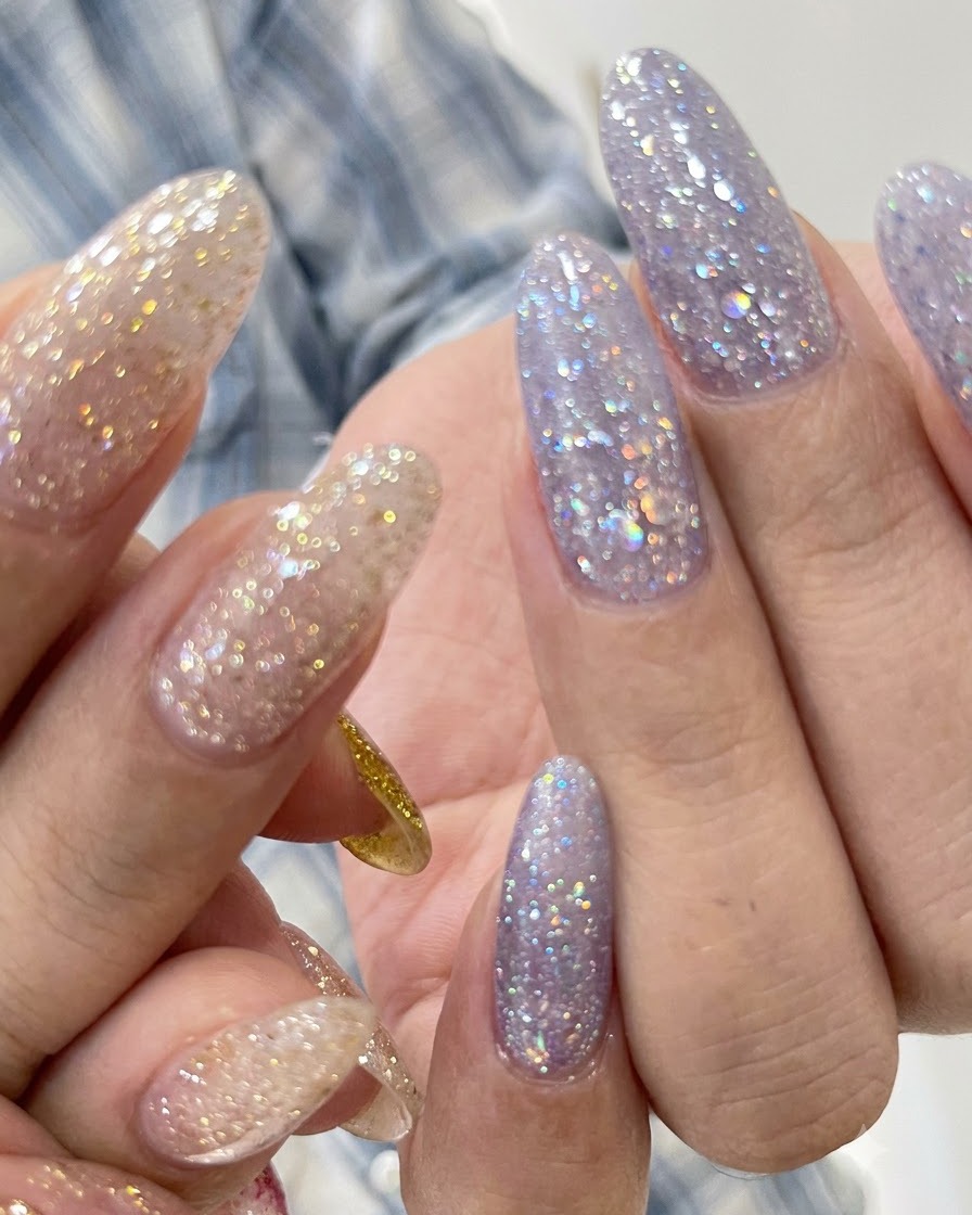 Una vista de cerca de las uñas texturizadas con glitter morado con una línea de cutícula limpia.
