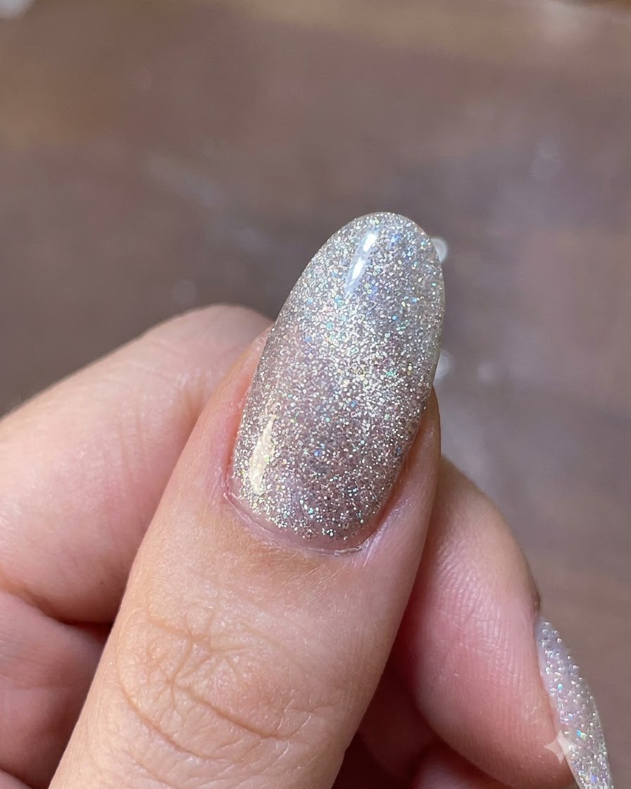 Una herramienta magnética flotando sobre una uña de gel brillante para desplazar las partículas metálicas de purpurina a su lugar.