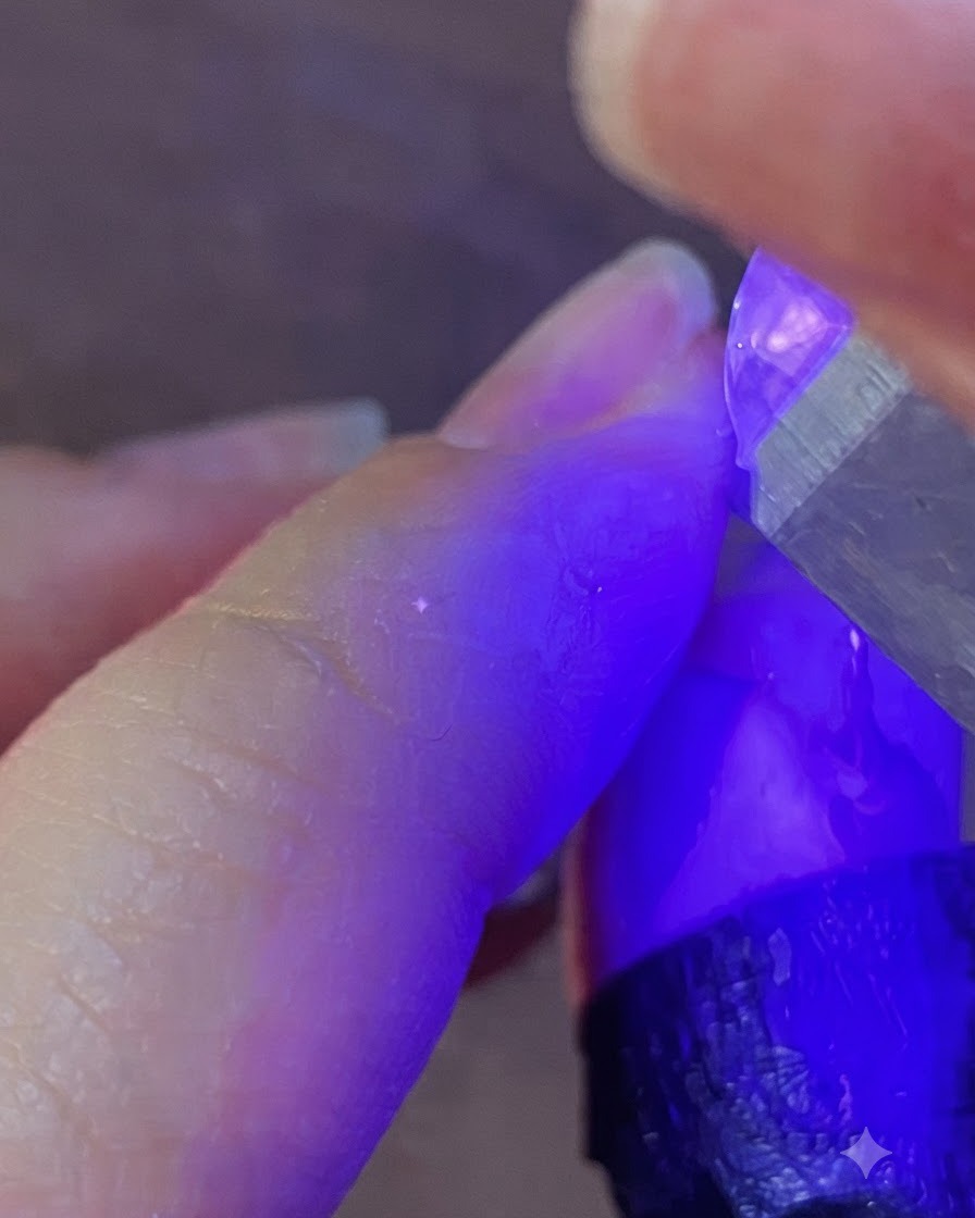 Una lámpara de uñas portátil UV LED proyectando luz morada sobre una uña para curar el gel.