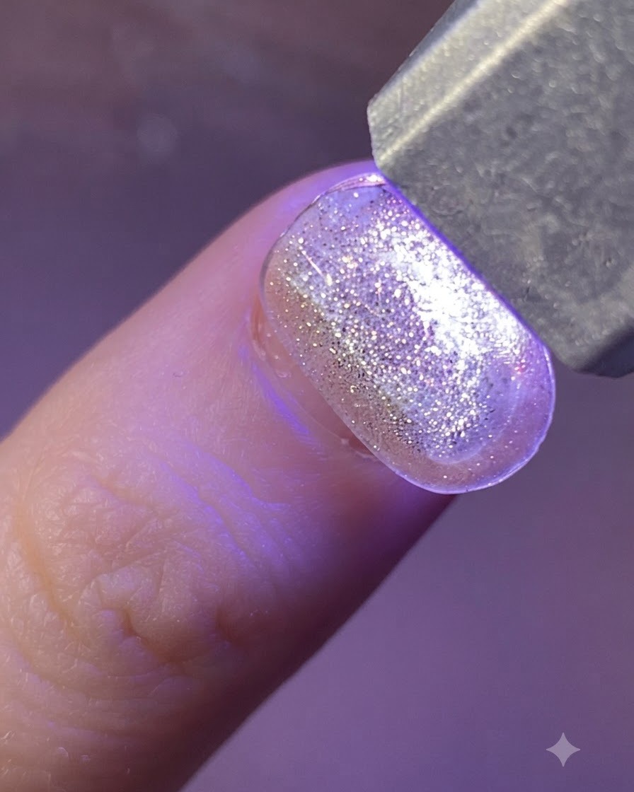 Unas pinzas metálicas levantando una pegatina de estrella holográfica desde una lámina transparente.