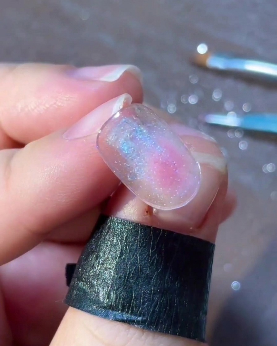 Una vista detallada de pequeños puntos y copos coloridos dispuestos delicadamente alrededor de un diseño de arte de uñas con estrella plateada.