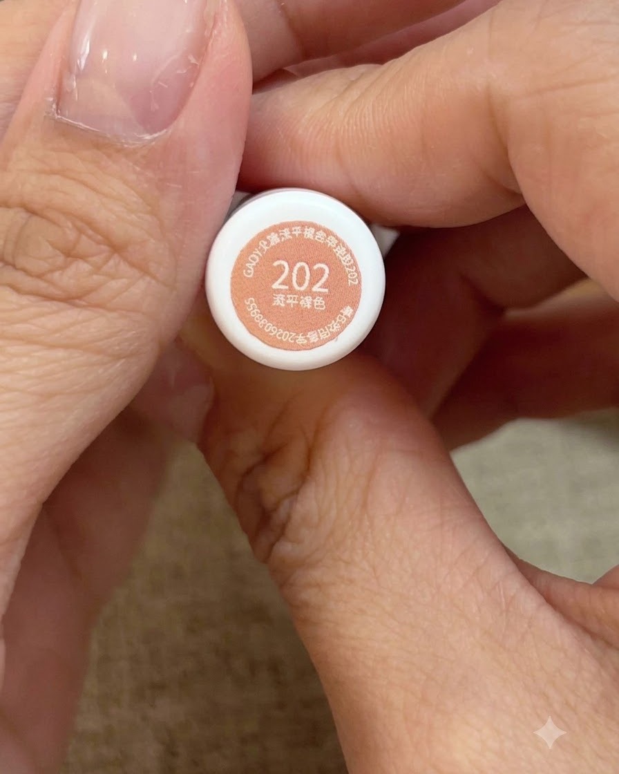 Una vista de cerca de unas manos sosteniendo el frasco número 202 de esmalte en gel rosa melocotón.
