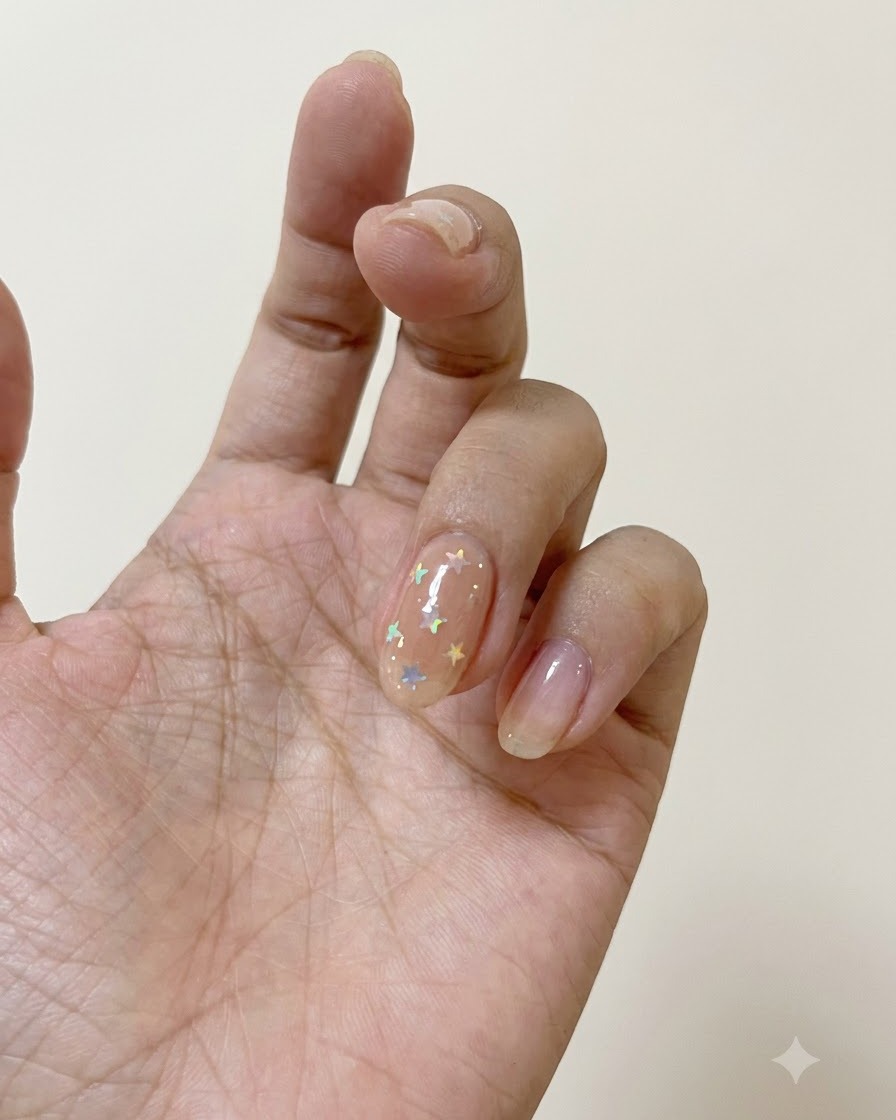 Un pincel de uñas aplicando la capa superior mate sobre una uña decorada con estrellas polarizadas.