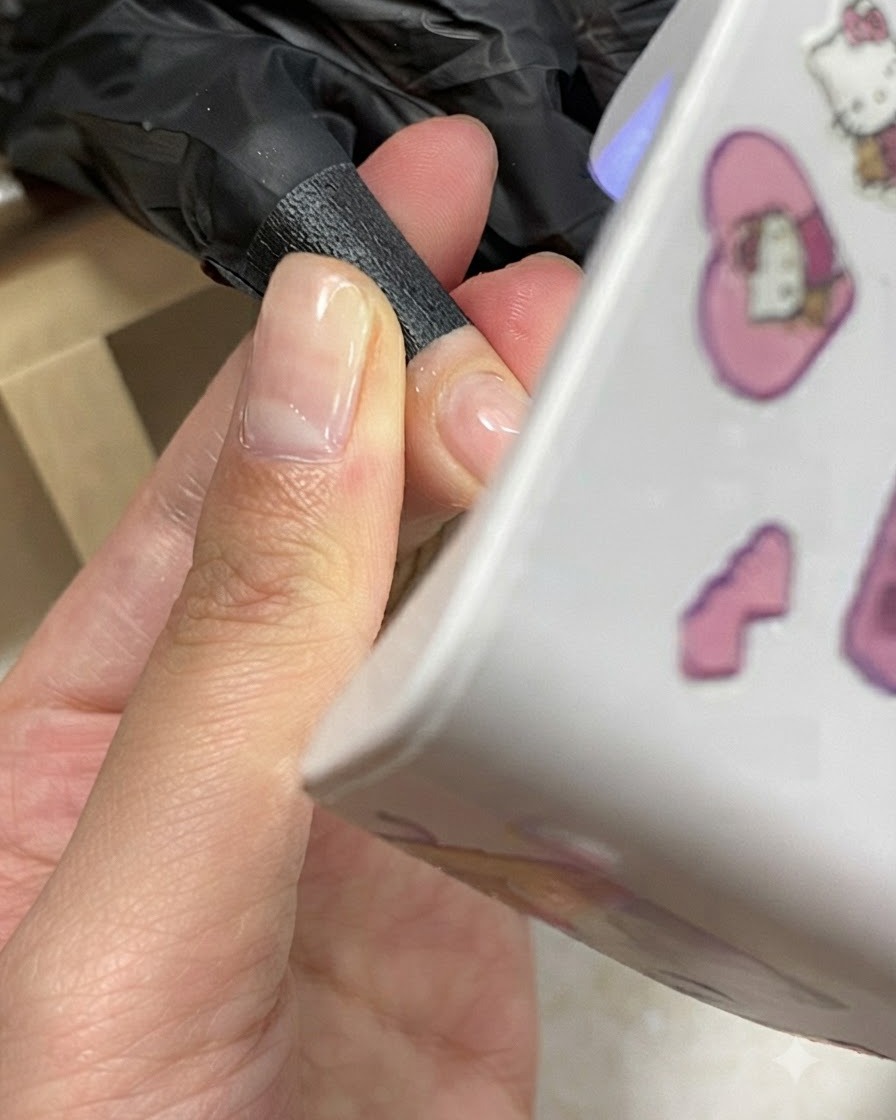 Una mano posicionada debajo de una mini lámpara UV/LED de uñas compacta durante un proceso de curado de gel.