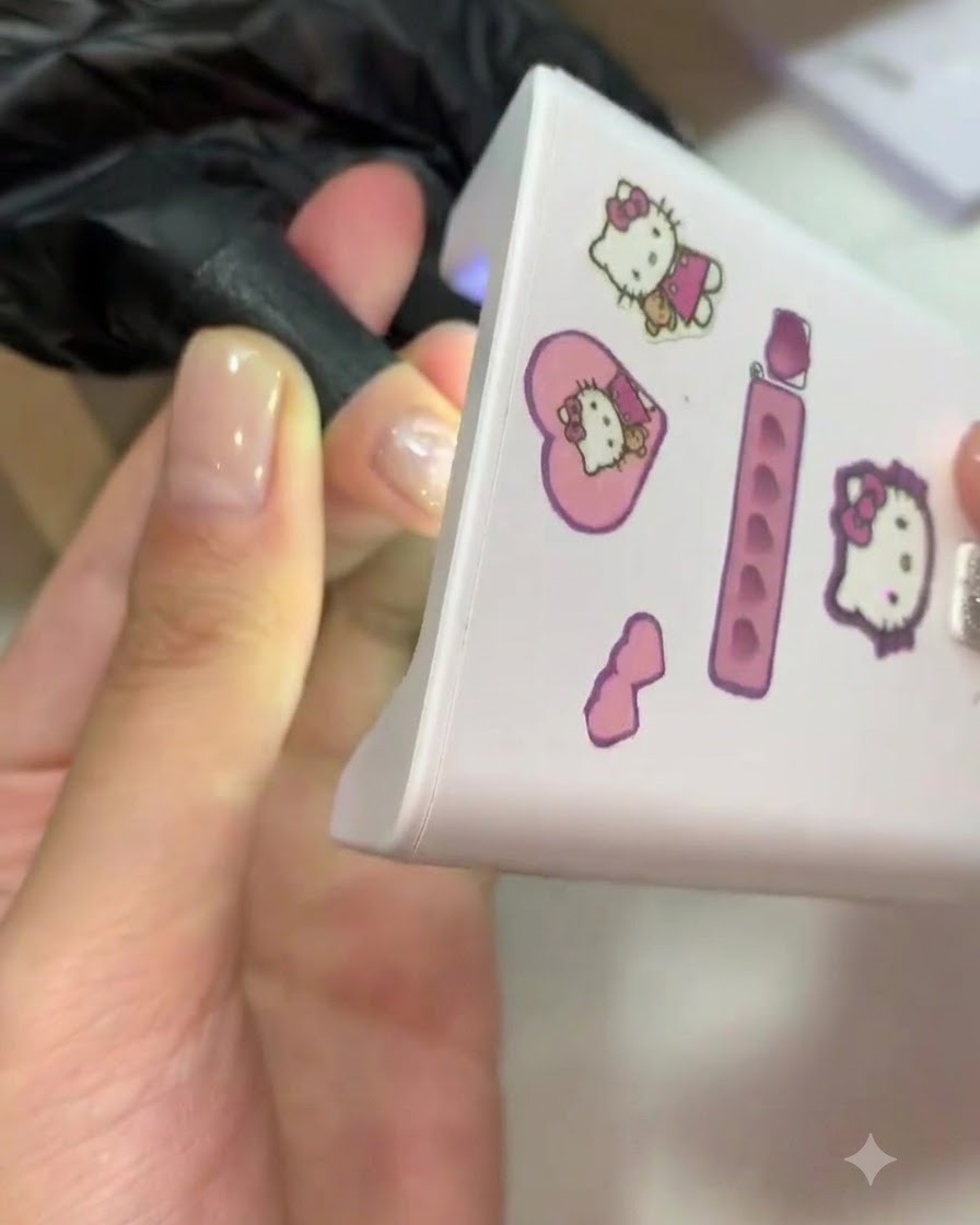 Un dedo colocado dentro de una mini lámpara UV/LED rosa para el curado.