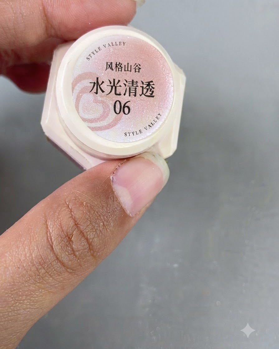 Un primer plano de una mano sosteniendo un frasco pequeño de gel cat-eye translúcido rosa etiquetado con el número 06.