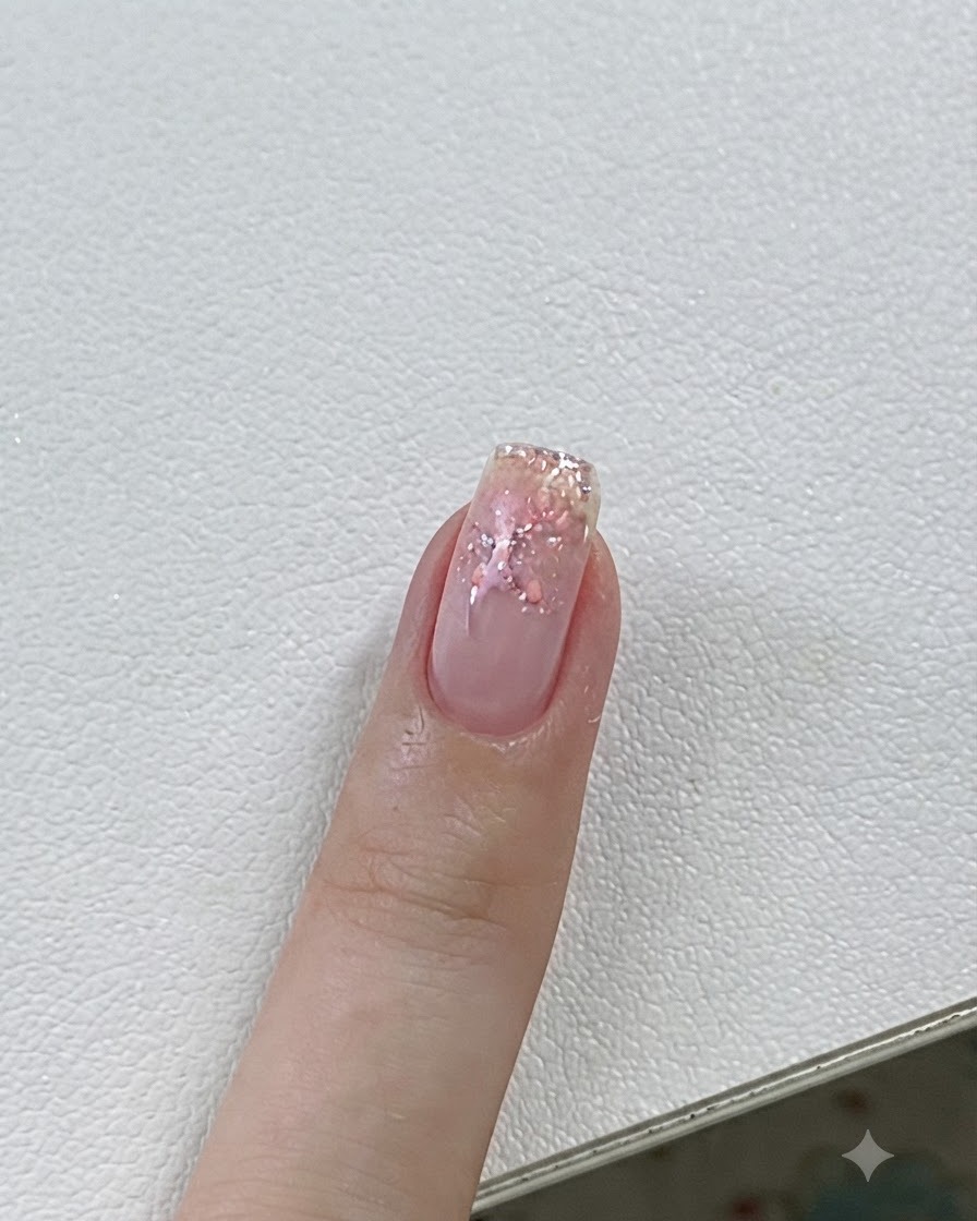 Primer plano de una uña curándose bajo una lámpara UV/LED con detalles de gel rosa y estrellas.