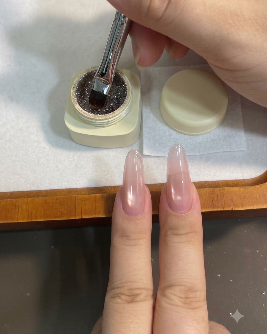 Un pincel de gel plano sumergiéndose en un tarro pequeño de gel de purpurina brillante color marrón café.