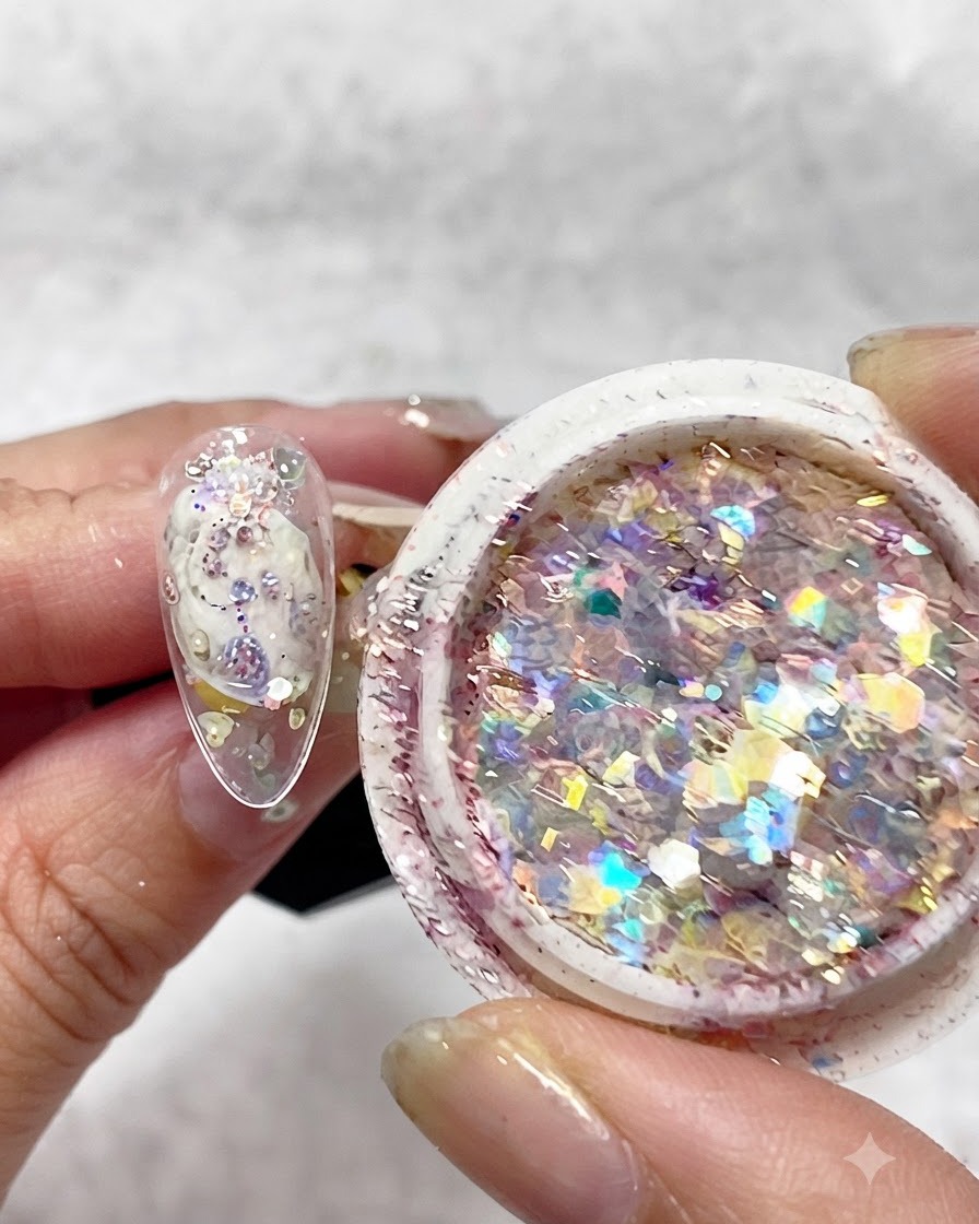 Un bloque pulidor de uñas frotándose contra la superficie de una uña postiza transparente montada en un soporte.