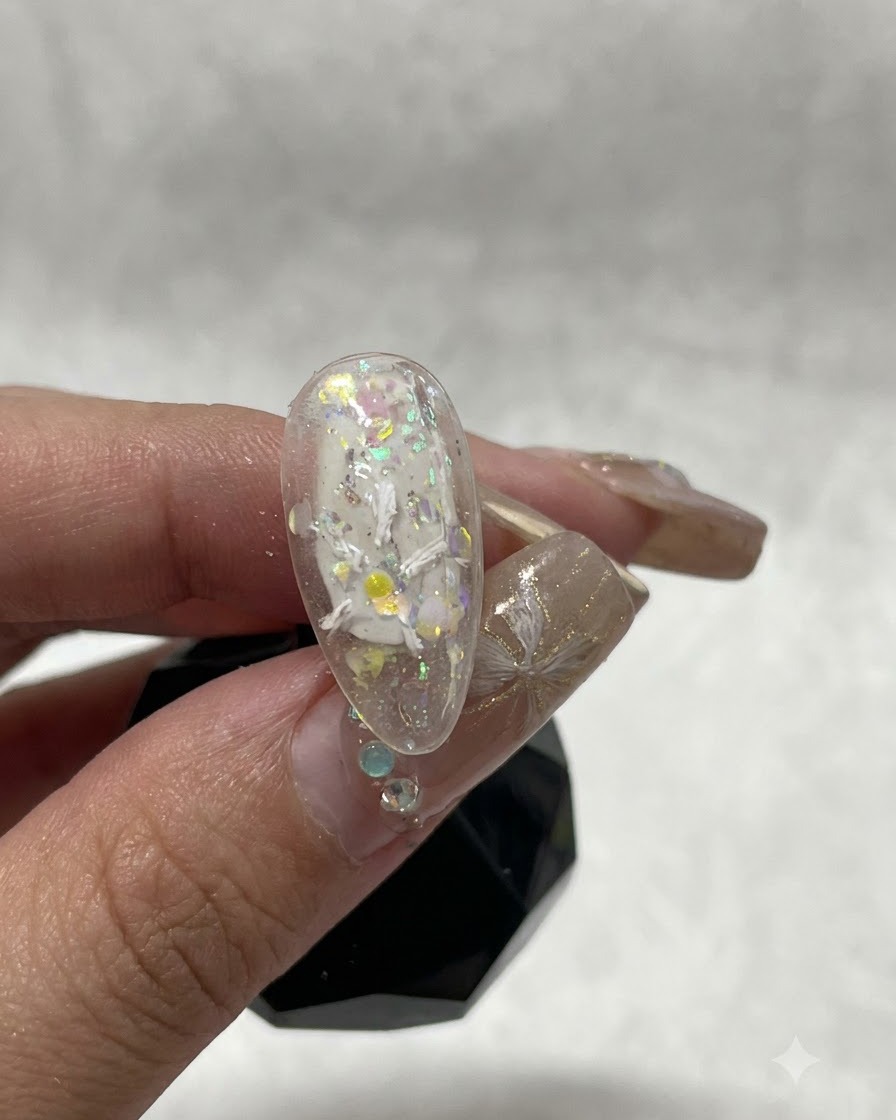 Una vista de cerca de una uña que muestra los trazos iniciales de gel de yeso blanco que forman el comienzo de un diseño floral.