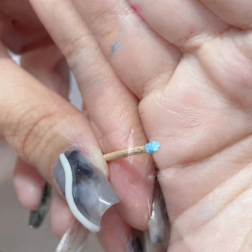 Un diminuto capullo de rosa azul cerrado esculpido en el extremo de un palillo.