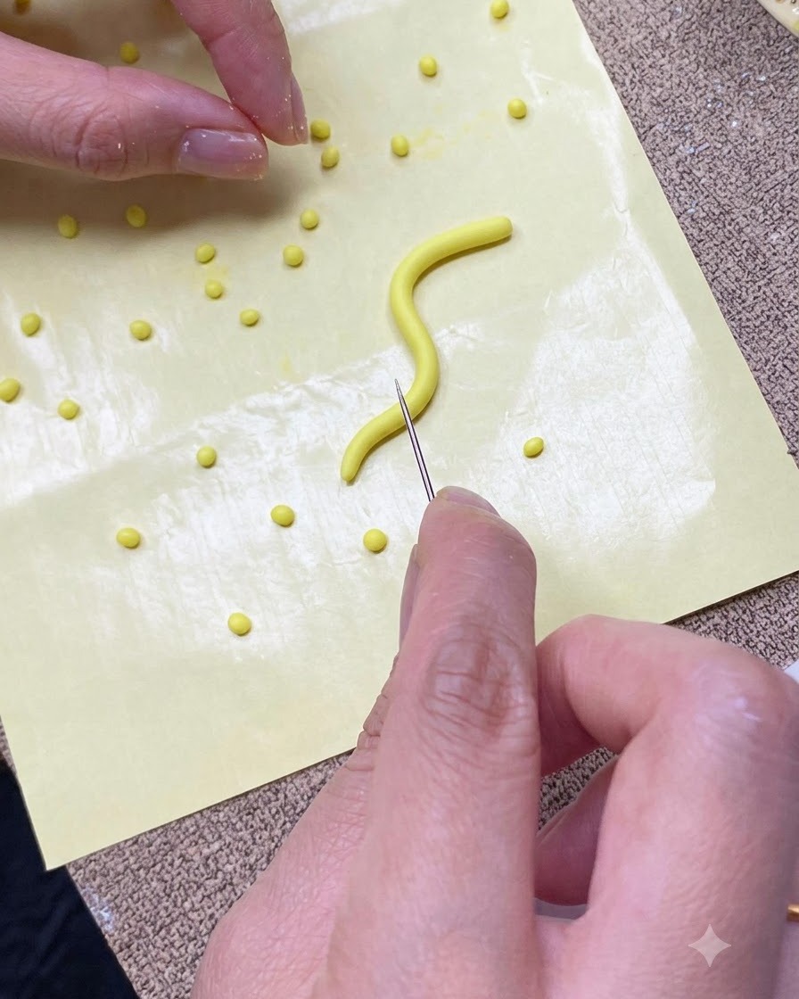 Primer plano de unas manos cortando una tira de gel amarillo en porciones pequeñas sobre una estera de silicona amarilla con una herramienta de aguja.