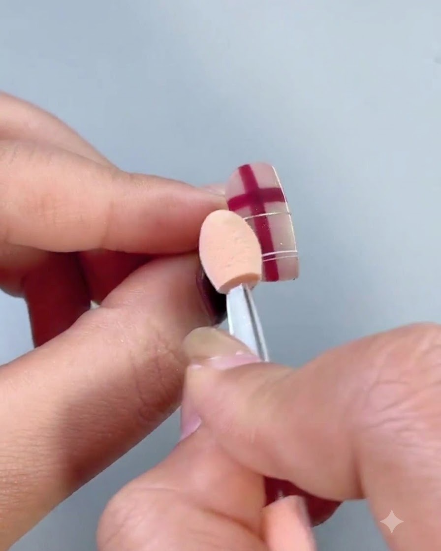 Una brocha esponjosa para polvo barriendo partículas sueltas de polvo metálico de una uña decorada.