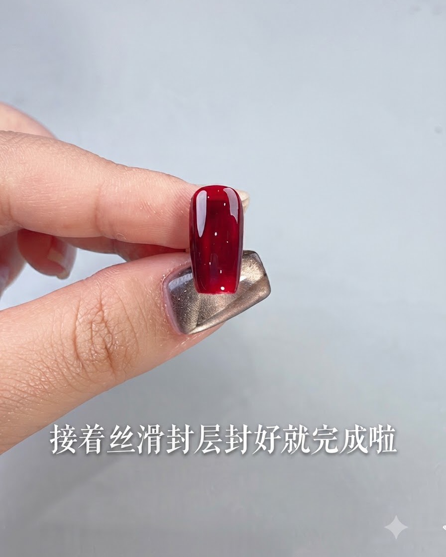Una sola uña terminada con esmalte de gel rojo sangre de buey brillante sostenida por un dedo contra un fondo claro.